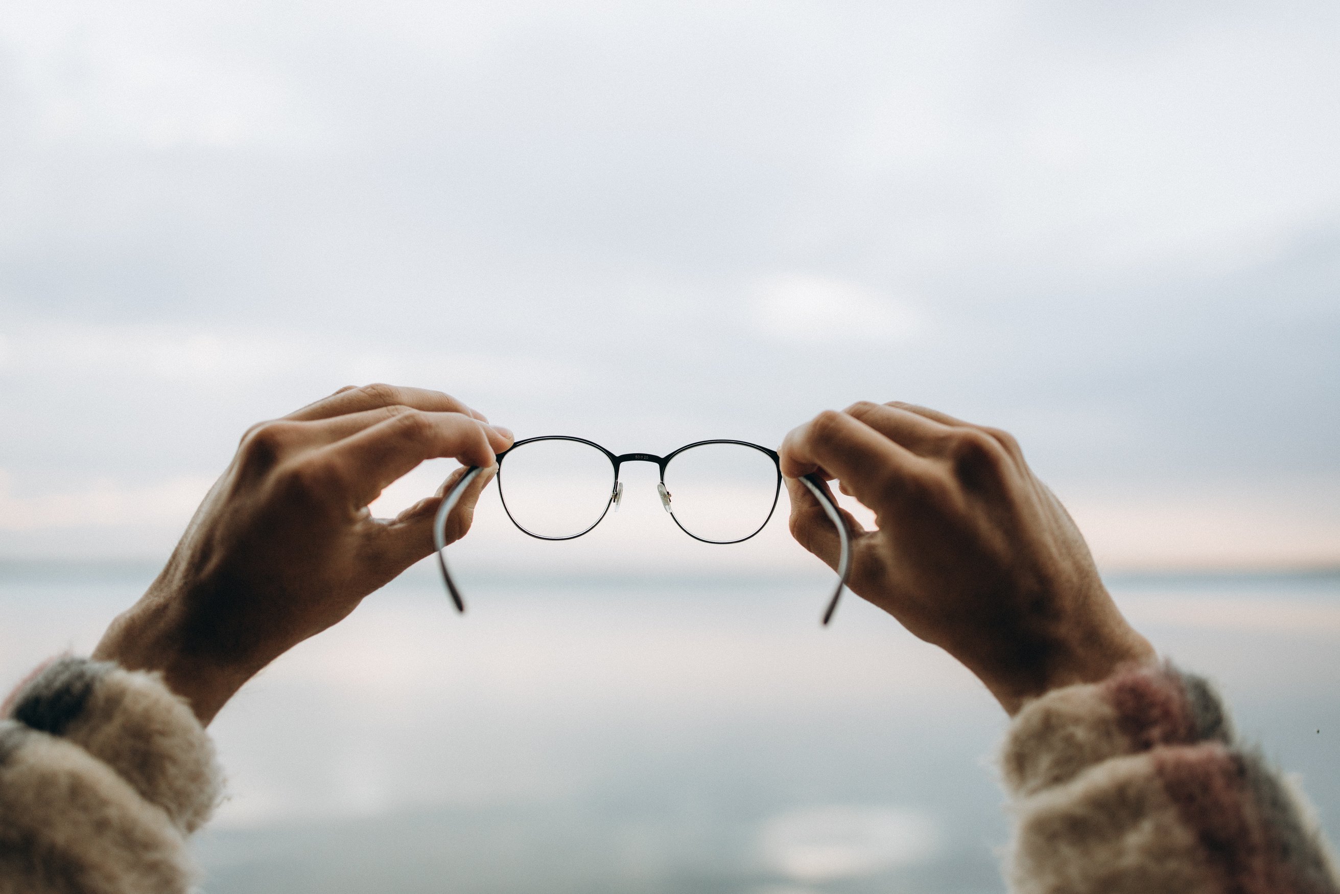 A Person Holding a Pair of Black Framed Eyeglasses